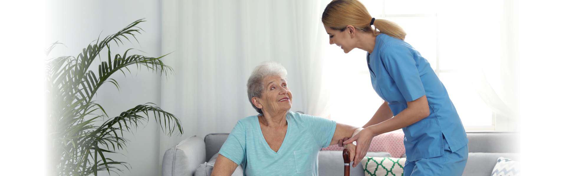 Nurse assisting elderly women with cane indoors